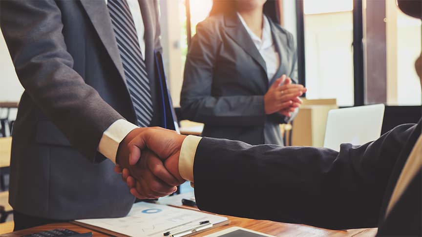 diverse business professionals shaking hands over desk